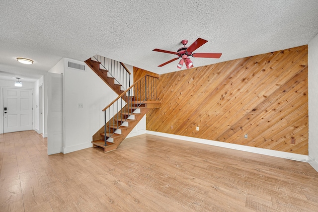 interior space featuring baseboards, ceiling fan, wood-type flooring, and visible vents