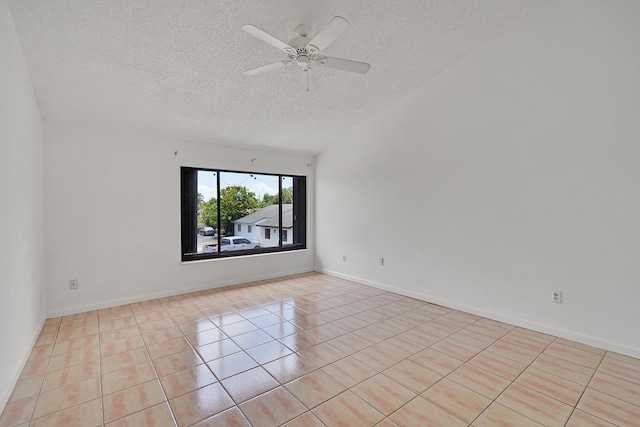 spare room with a ceiling fan, light tile patterned flooring, and a textured ceiling