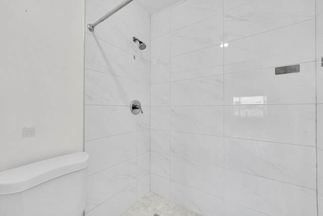 bathroom with a tile shower and toilet