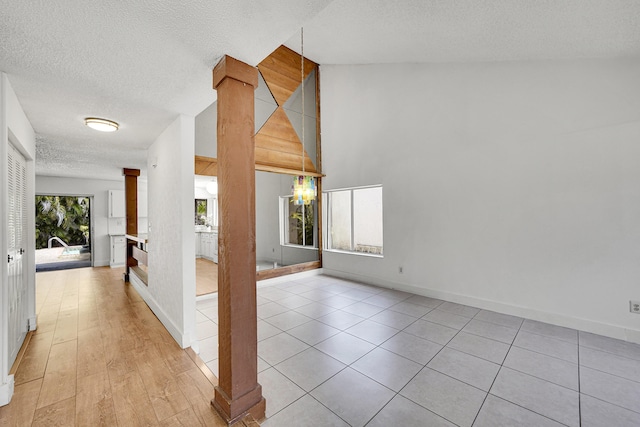 interior space featuring ornate columns, a textured ceiling, and baseboards