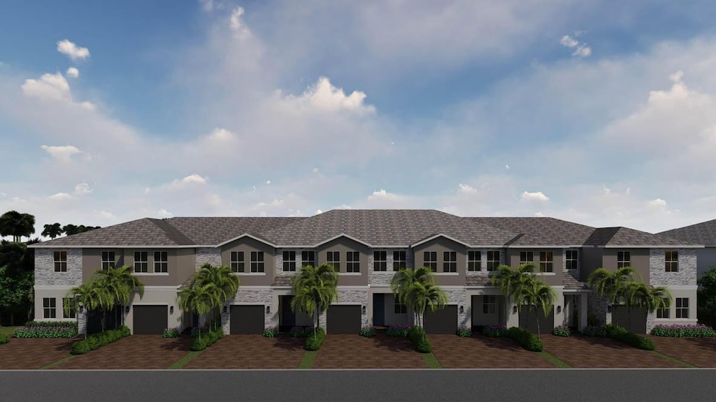 townhome / multi-family property with stucco siding, driveway, and stone siding