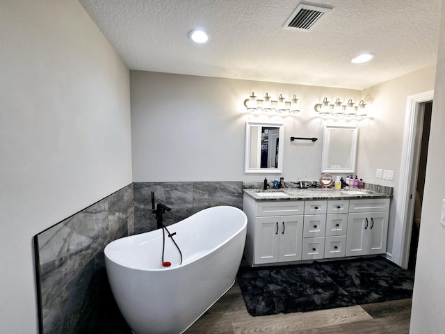 603 NW 11th Ave, Okeechobee, FL 34972 - bathroom with tile walls, wood finished floors, a textured ceiling, and visible vents