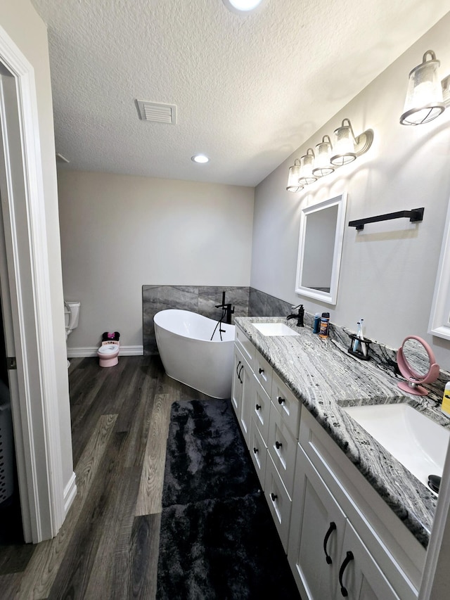 603 NW 11th Ave, Okeechobee, FL 34972 - bathroom with double vanity, a textured ceiling, a sink, and wood finished floors