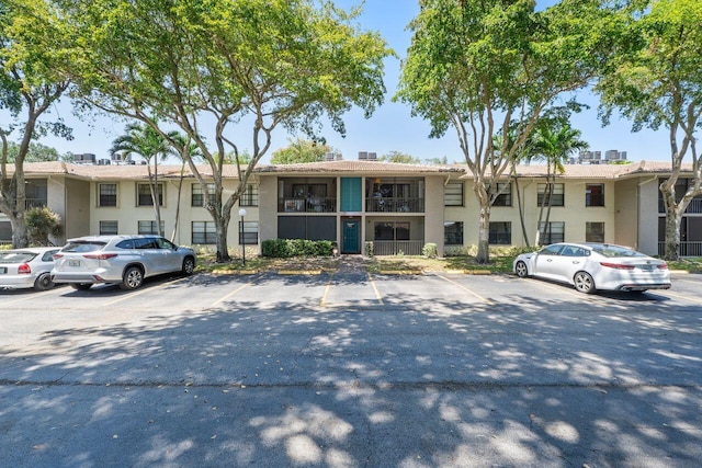 9960 Pineapple Tree Dr Unit 107, Boynton Beach, FL 33436 - view of front facade with uncovered parking, stucco siding, and a chimney