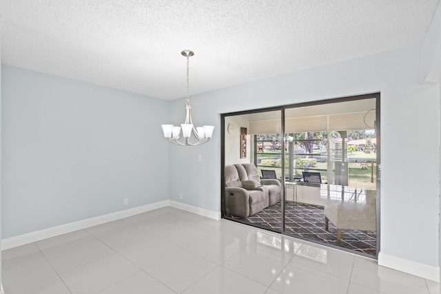 interior space featuring a textured ceiling, a notable chandelier, baseboards, and tile patterned flooring