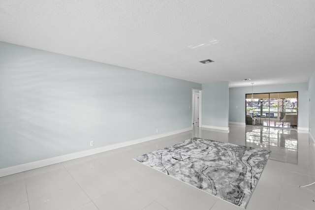 spare room with baseboards, a textured ceiling, and visible vents