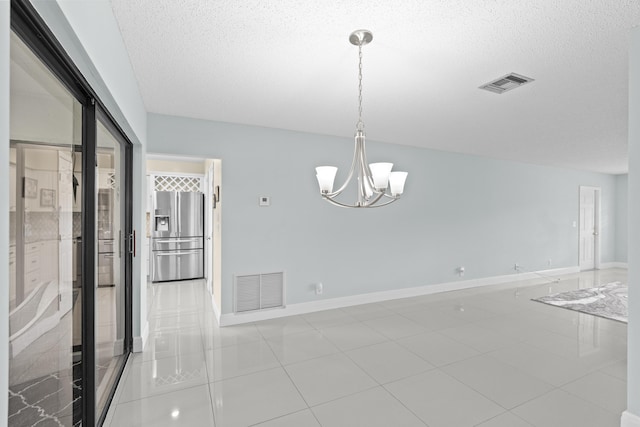 unfurnished dining area with a notable chandelier, a textured ceiling, and visible vents