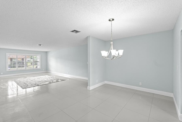 empty room with visible vents, baseboards, a textured ceiling, tile patterned floors, and a chandelier