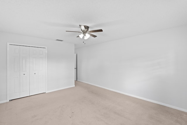 unfurnished bedroom with a ceiling fan, visible vents, baseboards, a closet, and light carpet