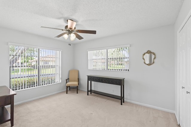 sitting room with a ceiling fan, a textured ceiling, baseboards, and carpet