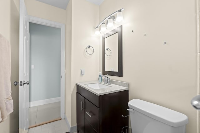half bath with toilet, tile patterned floors, and vanity