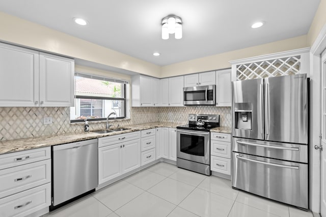 kitchen featuring decorative backsplash, light stone counters, a sink, light tile patterned floors, and stainless steel appliances