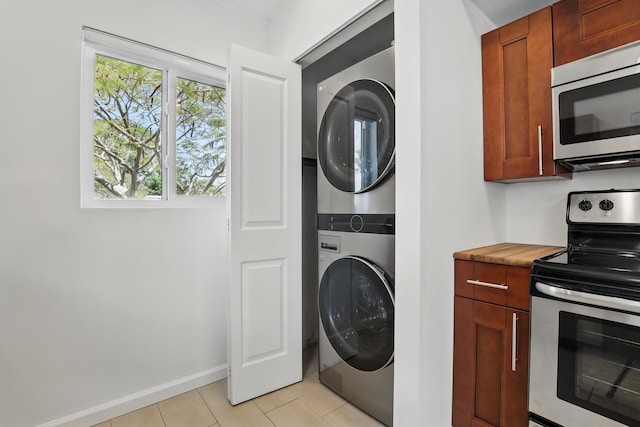 1225 15th Ave N, Lake Worth Beach, FL 33460 - washroom featuring stacked washer and clothes dryer, light tile patterned flooring, and baseboards