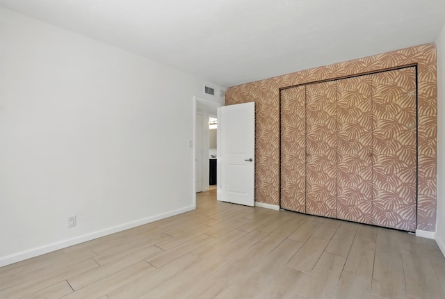 unfurnished bedroom with baseboards, wood finished floors, and visible vents