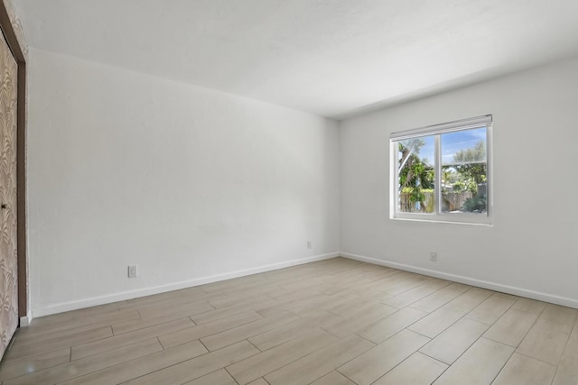 empty room with baseboards and light wood-style flooring