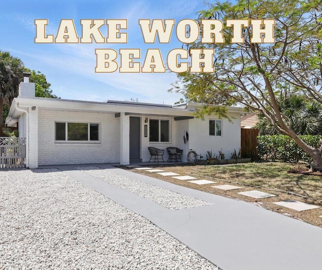 1225 15th Ave N, Lake Worth Beach, FL 33460 - view of front of property with fence, a chimney, and brick siding