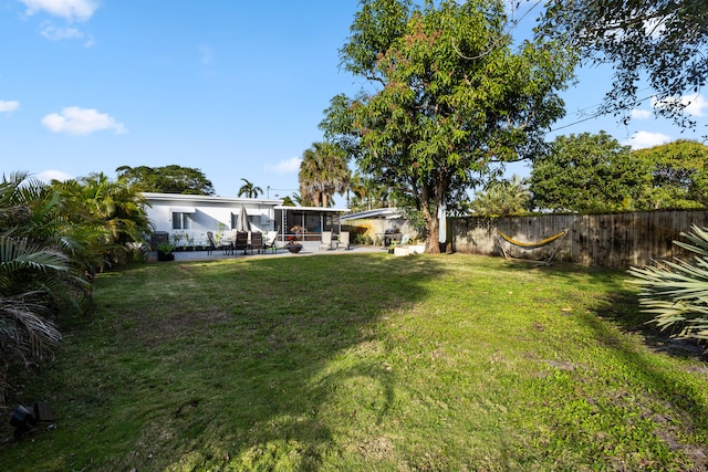view of yard with a sunroom, fence, and a patio