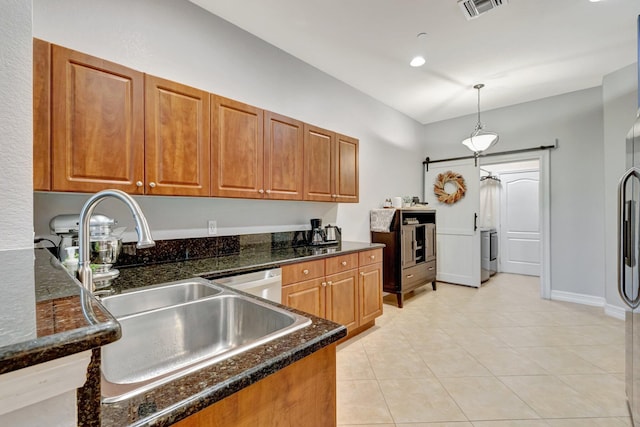 kitchen with brown cabinetry, a sink, and light tile patterned floors