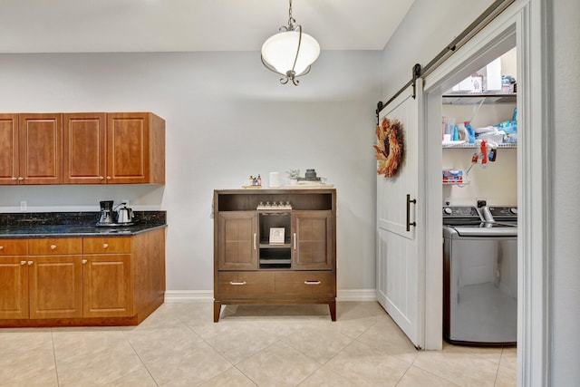 kitchen with a barn door, brown cabinetry, light tile patterned floors, and separate washer and dryer