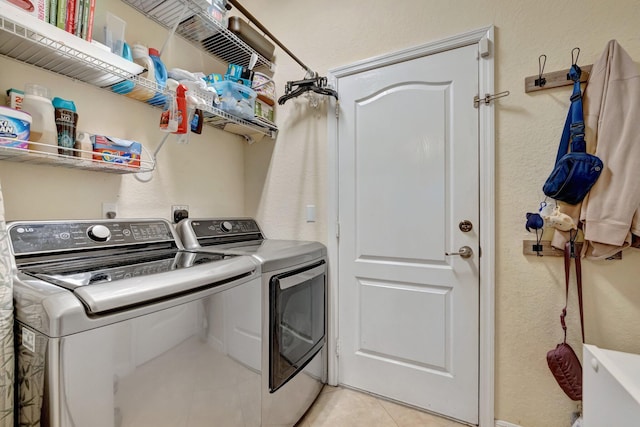 laundry area with washer and dryer, light tile patterned floors, and a textured wall