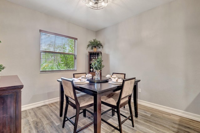 dining space featuring light wood-style flooring and baseboards