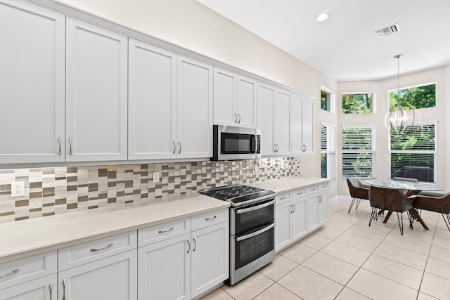 8673 Carmel Mountain Way, Boynton Beach, FL 33473 - kitchen featuring stainless steel appliances, tasteful backsplash, light countertops, light tile patterned floors, and decorative light fixtures