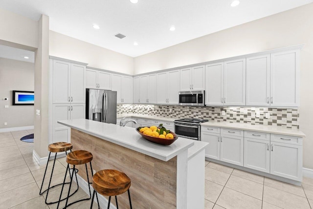 8673 Carmel Mountain Way, Boynton Beach, FL 33473 - kitchen featuring appliances with stainless steel finishes, light tile patterned flooring, a kitchen breakfast bar, tasteful backsplash, and recessed lighting