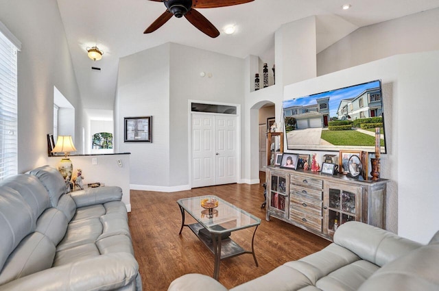 living area featuring a ceiling fan, arched walkways, high vaulted ceiling, wood finished floors, and baseboards