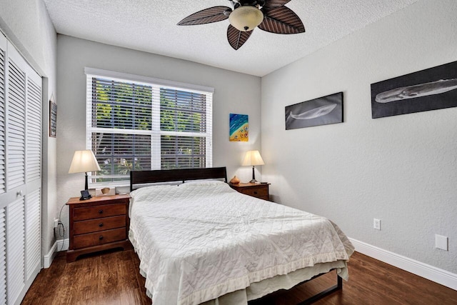 bedroom with a closet, wood finished floors, baseboards, a textured wall, and a textured ceiling