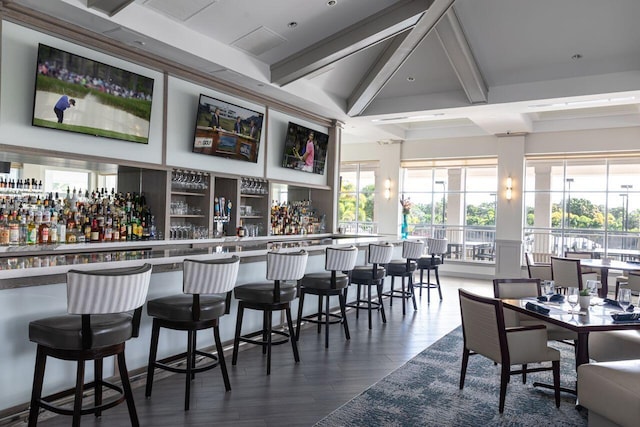 indoor dry bar featuring beam ceiling and dark wood-type flooring