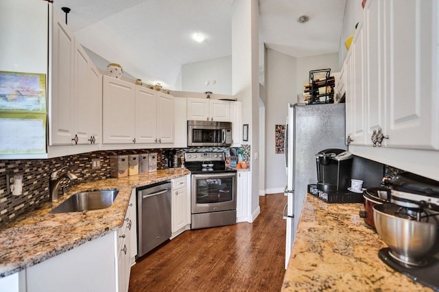 kitchen with stainless steel appliances, a sink, tasteful backsplash, white cabinets, and light stone counters