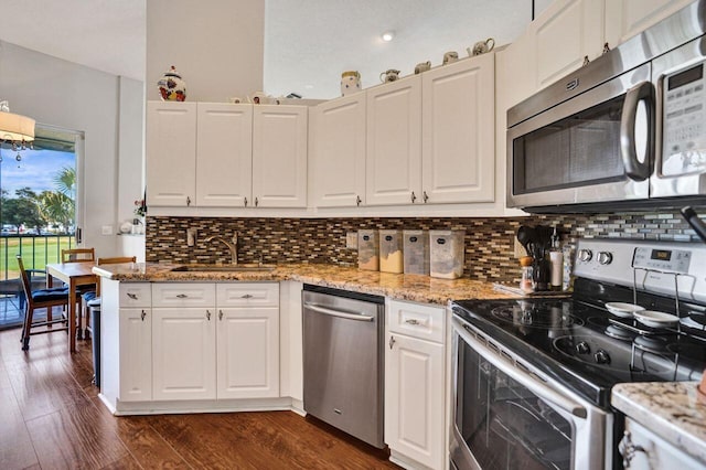 kitchen with stainless steel appliances, white cabinets, a sink, dark wood-style flooring, and decorative backsplash