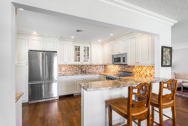 3980 Quail Ridge Dr Egret, Unit Egret, Boynton Beach, FL 33436 - kitchen with crown molding, light stone countertops, appliances with stainless steel finishes, a peninsula, and glass insert cabinets