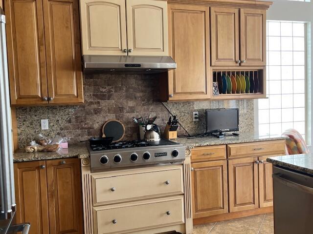 kitchen featuring stainless steel gas cooktop, dishwasher, under cabinet range hood, light stone counters, and backsplash