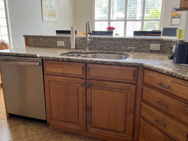 kitchen featuring a sink, dishwasher, brown cabinets, and a healthy amount of sunlight