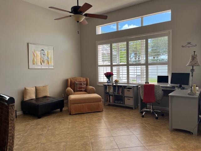 home office with ceiling fan, light tile patterned flooring, and a towering ceiling