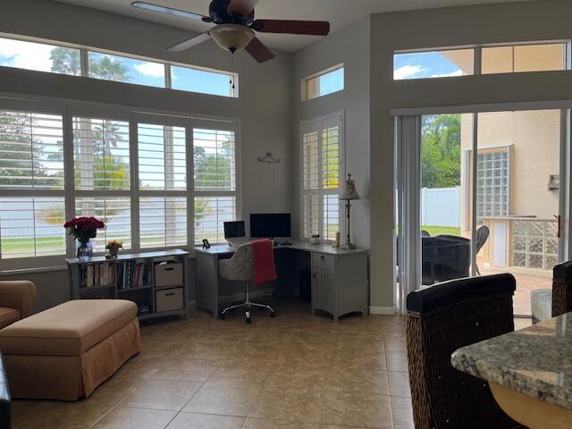 home office featuring light tile patterned floors, a water view, and ceiling fan