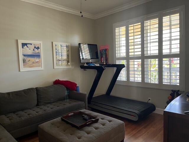 workout area featuring baseboards, plenty of natural light, ornamental molding, and wood finished floors