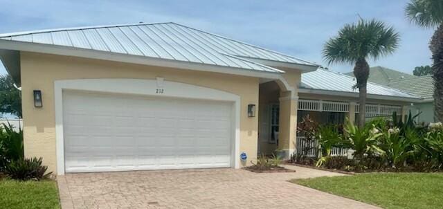 212 NW Pleasant Grove Way, Port Saint Lucie, FL 34986 - view of front of property with stucco siding, a standing seam roof, driveway, a metal roof, and an attached garage