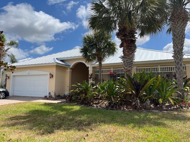 212 NW Pleasant Grove Way, Port Saint Lucie, FL 34986 - single story home featuring stucco siding, an attached garage, a front lawn, driveway, and a metal roof