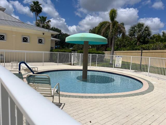 community pool with a patio area and fence