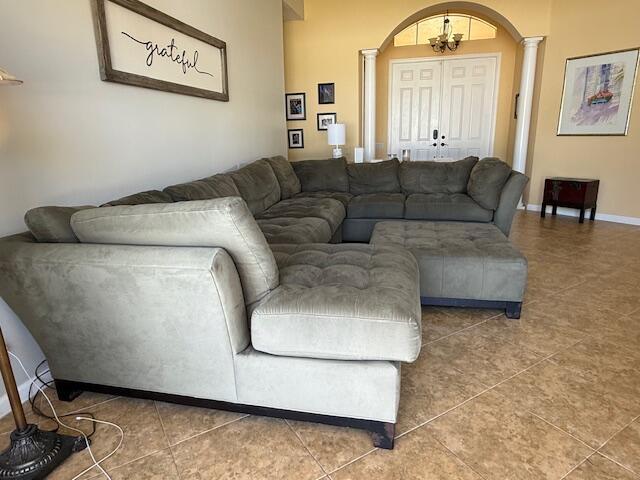 212 NW Pleasant Grove Way, Port Saint Lucie, FL 34986 - living room with ornate columns, arched walkways, tile patterned flooring, and a chandelier