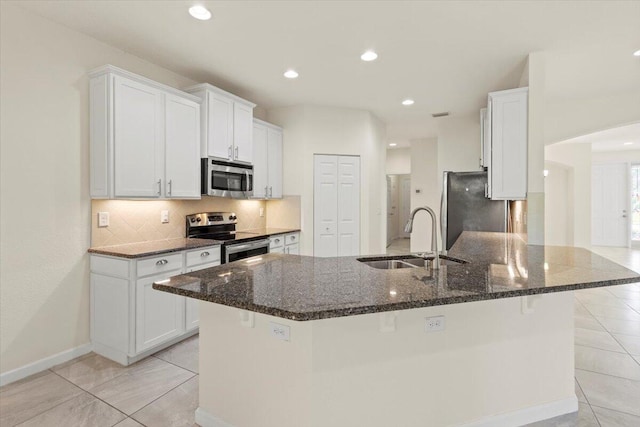 12133 SW Aventino Dr, Port Saint Lucie, FL 34987 - kitchen with appliances with stainless steel finishes, a sink, backsplash, white cabinets, and dark stone countertops