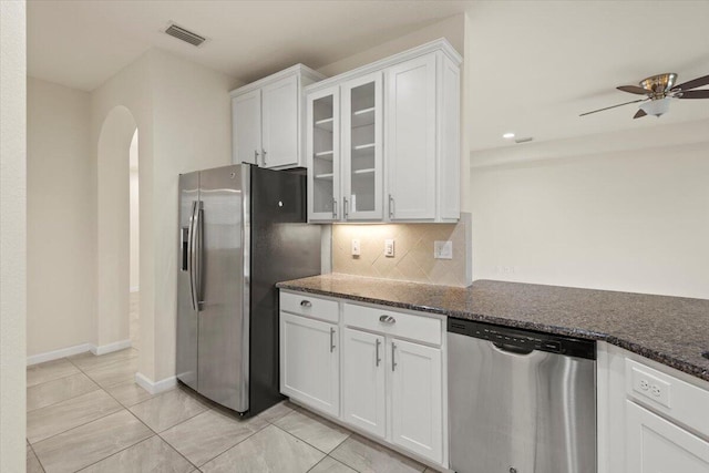 12133 SW Aventino Dr, Port Saint Lucie, FL 34987 - kitchen featuring appliances with stainless steel finishes, arched walkways, white cabinets, and dark stone countertops