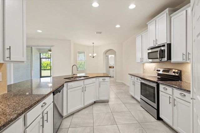 12133 SW Aventino Dr, Port Saint Lucie, FL 34987 - kitchen featuring appliances with stainless steel finishes, a sink, arched walkways, backsplash, and white cabinetry