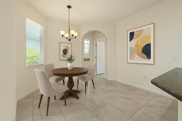 12133 SW Aventino Dr, Port Saint Lucie, FL 34987 - dining area featuring arched walkways, a chandelier, light tile patterned floors, and baseboards