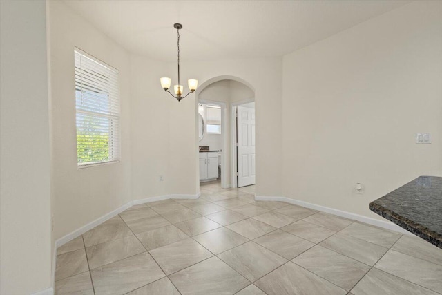 12133 SW Aventino Dr, Port Saint Lucie, FL 34987 - unfurnished dining area with arched walkways, light tile patterned floors, a chandelier, and baseboards
