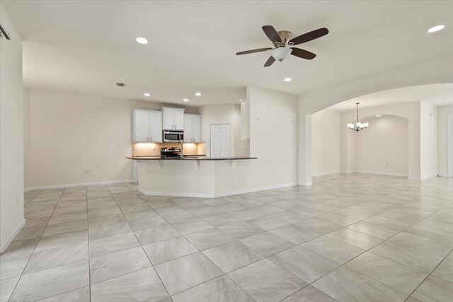 12133 SW Aventino Dr, Port Saint Lucie, FL 34987 - unfurnished living room featuring recessed lighting, a chandelier, a ceiling fan, baseboards, and arched walkways