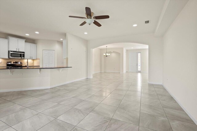 12133 SW Aventino Dr, Port Saint Lucie, FL 34987 - unfurnished living room featuring arched walkways, ceiling fan, recessed lighting, baseboards, and a chandelier