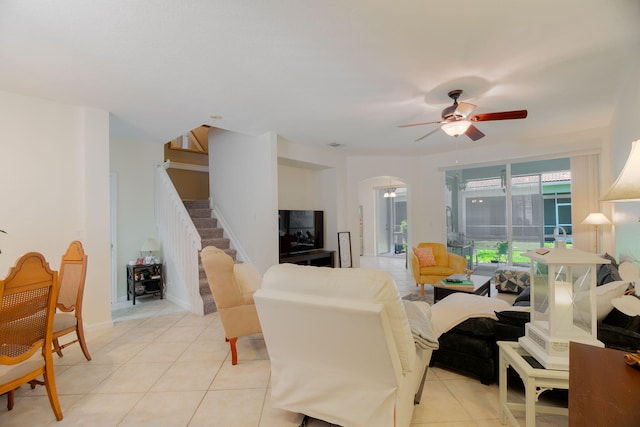 living room with arched walkways, stairs, ceiling fan, and light tile patterned floors
